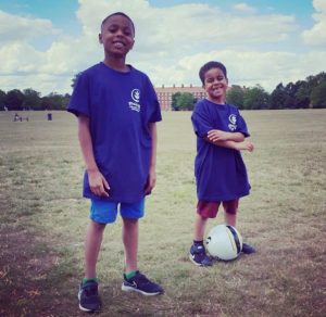 2 young boys standing with a football